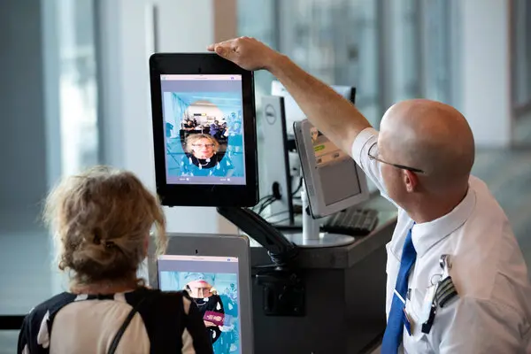 women using facial recognition to board a flight. Assisted by man employee
