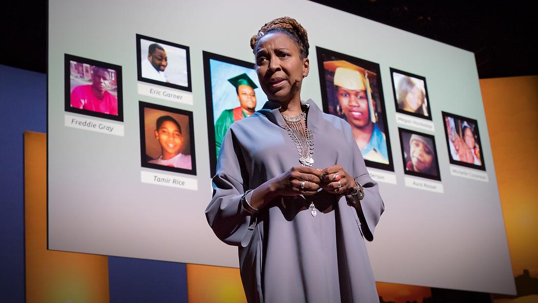Kimberle Crenshaw giving TED Talk infront of a screen. Sreen shows muliple images of people.
